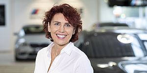  Eine lächelnde Frau mit roten Locken in einem BMW Autohaus.