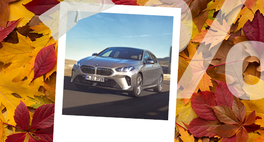 Ein Werbebanner im Herbst-Design auf einem Hintergrund aus buntem Herbstlaub in Gelb- und Rottönen. In der Mitte befindet sich ein mit Klebestreifen befestigtes Sofortbild (Polaroid), das einen silbergrauen BMW auf einer Straße bei sonnigem Wetter zeigt. Auf der rechten Seite liegt ein großes, halbtransparentes weißes Prozentzeichen (%) über den Blättern.