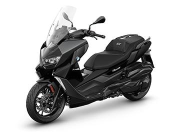 Das Bild präsentiert den Scooter in einer sauberen Studioaufnahme in der Farbe Blackstorm metallic. Im Gegensatz zum C 400 X wirkt die Verkleidung hier deutlich voluminöser und eleganter. Die Sitzbank ist großzügig geschnitten und verfügt über eine kleine Rückenstütze für den Fahrer, die mit einem dezenten „GT“-Schriftzug bestickt ist. Die gesamte Formsprache ist harmonischer und weniger zerklüftet, was den luxuriösen „Gran Turismo“-Anspruch dieses Modells betont.