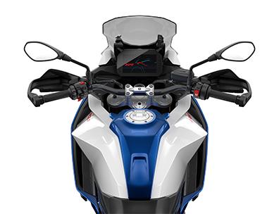  Auf dem Bild ist eine BMW F 900 XR abgebildet, ein mittelgroßes, blau-weißes und rotes Motorrad, das auf einem weißen Hintergrund steht.  Das Bild zeigt eine Nahaufnahme der Front des Motorrads, von der Perspektive eines Fahrers. Man sieht den Lenker mit Spiegeln, das beleuchtete Armaturenbrett, das BMW-Logo und den Tank. Es ist sauber und glänzt, als wäre es brandneu.