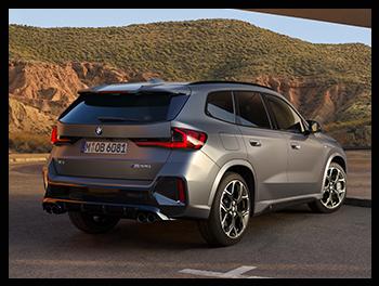 Rückansicht eines BMW X1 M35i in Mattgrau; markant sind die vier Endrohre (typisch für M-Modelle), der Diffusor und die scharf gezeichneten LED-Rückleuchten.