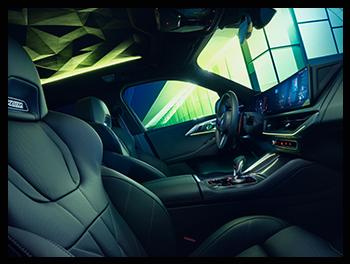 Der Innenraum des BMW XM 50e besticht durch den skulpturalen, beleuchteten Dachhimmel im Prismen-Design, M-Sportsitze mit XM-Logo und das fahrerorientierte Curved Display.