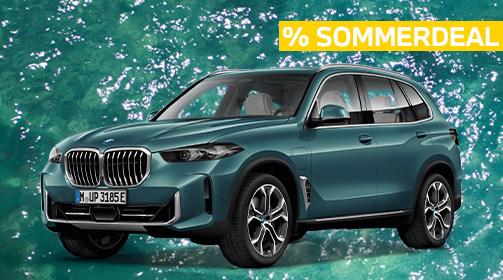 Ein türkisfarbener BMW X5 xDrive50e SUV steht auf einem türkisfarbenen Wasserhintergrund, der leichte Wellen zeigt. Das Fahrzeug ist leicht von vorne links aufgenommen, wodurch die Front mit dem Kühlergrill und die gesamte linke Fahrzeugseite mit den mehrspeichigen Felgen gut sichtbar sind. Oben rechts im Bild befindet sich ein gelbes Banner mit der Aufschrift „% SOMMERDEAL“ in Großbuchstaben. Das Fahrzeug wirkt robust und elegant zugleich.